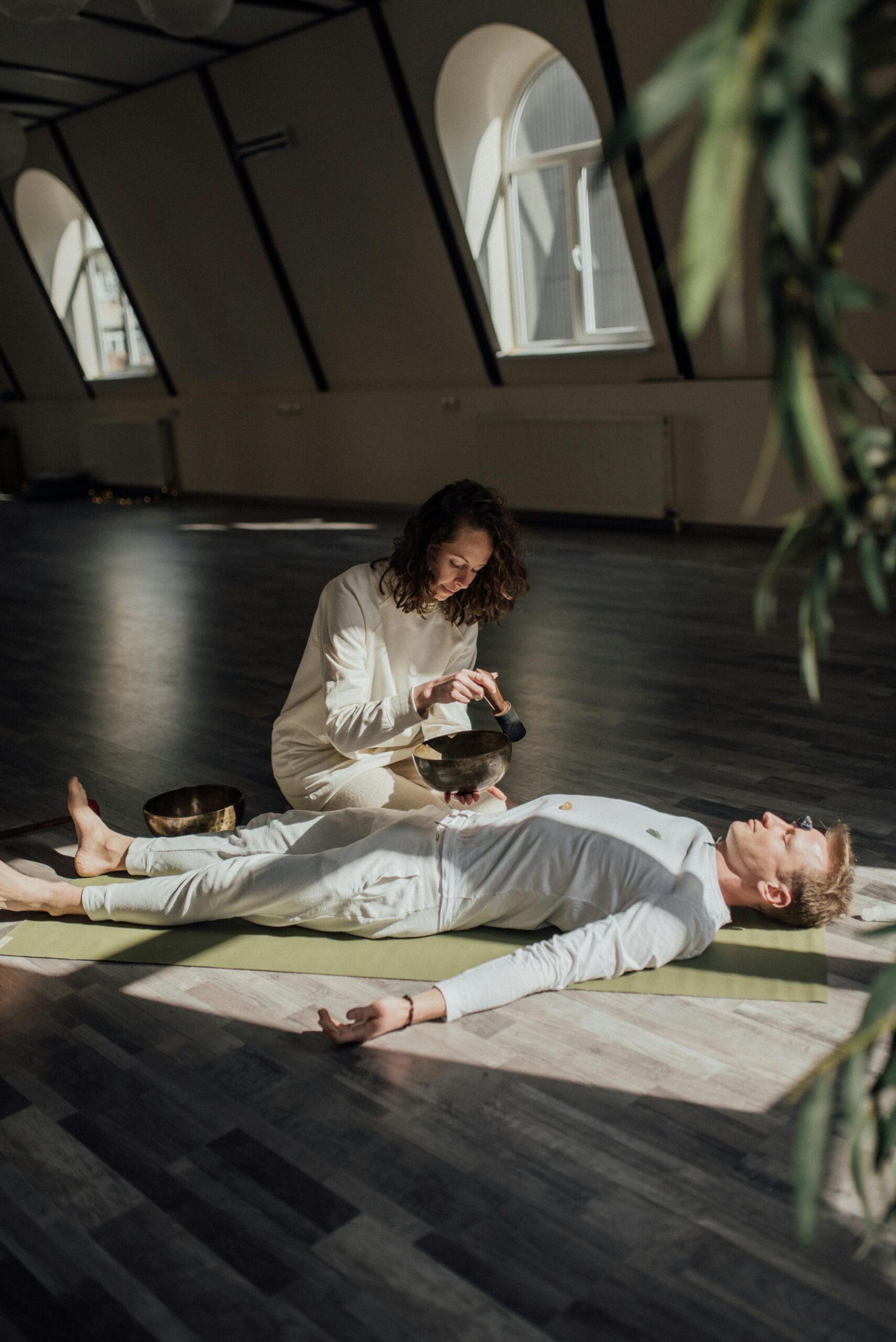 woman with sound bowl man laying on yoga mat